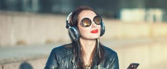 Hipster beautiful girl in leather jacket and glasses listening music outdoor